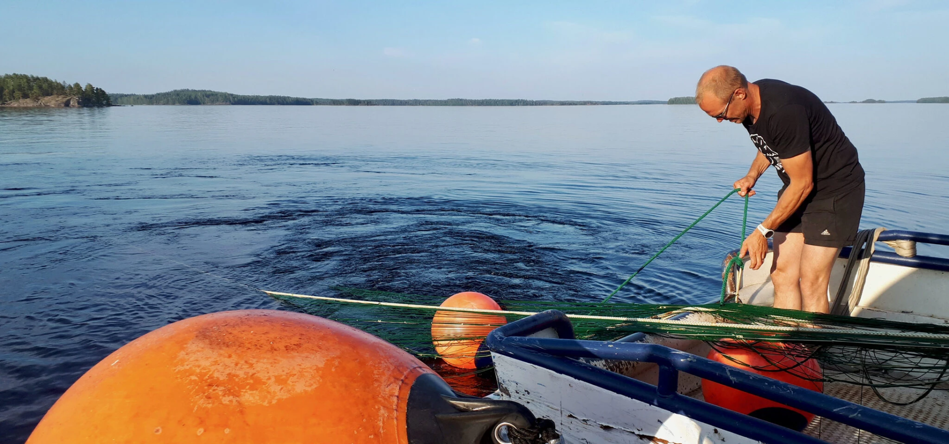 Mies vetää trooliverkkoa kalastusalukseen. 